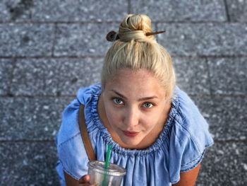 High angle portrait of young woman having drink on footpath