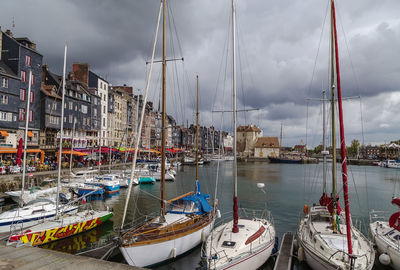 Sailboats moored in harbor against sky