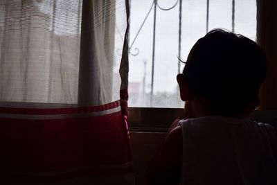 Rear view of silhouette man against window