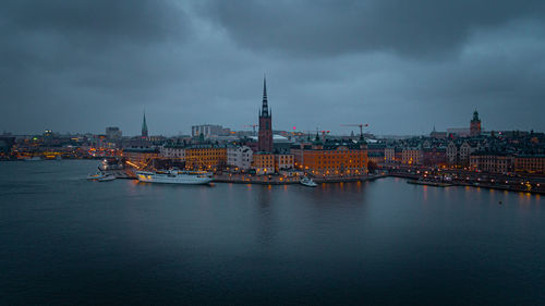 Buildings at waterfront against cloudy sky
