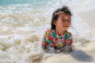 Cute girl playing in sea on shore at beach during sunny day