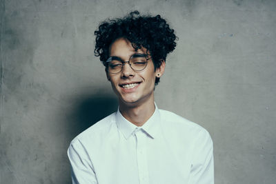 Portrait of smiling young man standing against wall