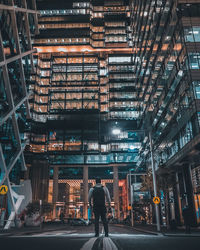 Rear view of man standing on city street at night