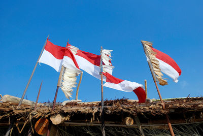 Low angle view of flags against clear blue sky