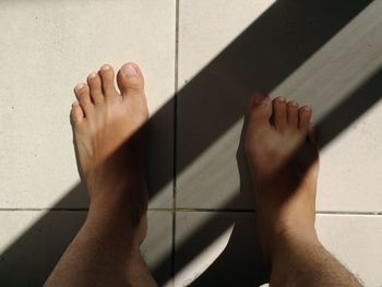 Low section of person legs on tiled floor