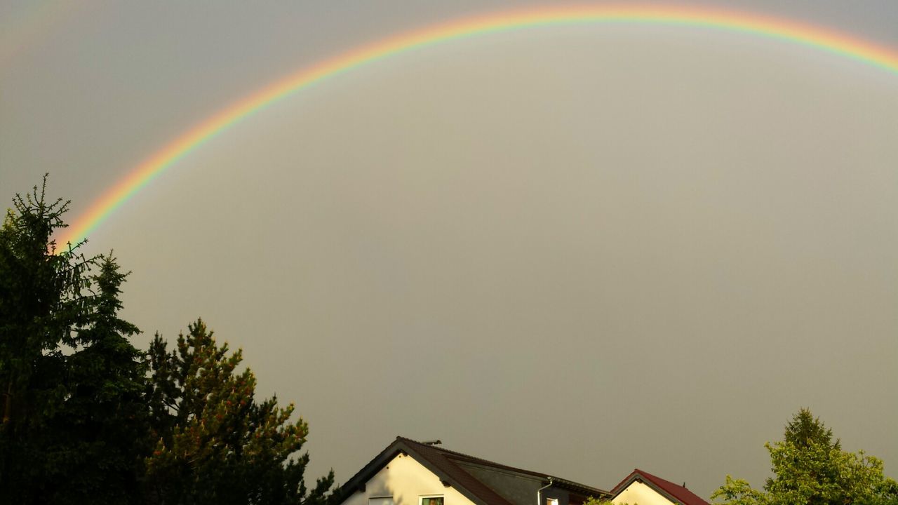 architecture, building exterior, built structure, rainbow, low angle view, house, sky, tree, high section, multi colored, residential structure, copy space, residential building, outdoors, nature, roof, no people, clear sky, beauty in nature, dusk