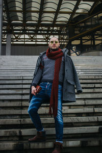 Portrait of man wearing warm clothing standing on steps outdoors