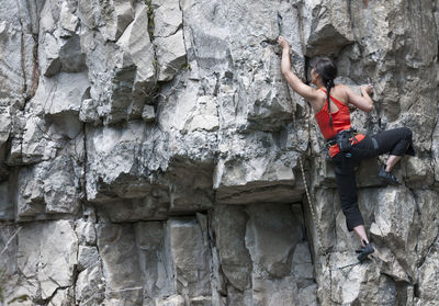 Woman climbing limestone rock face in swanage / uk