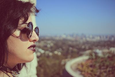 Close-up of woman wearing sunglasses against blue sky