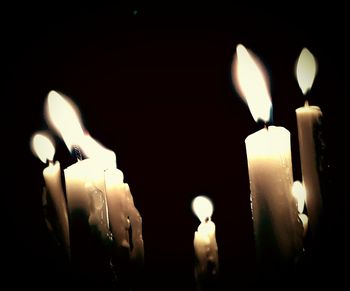 Close-up of lit candles in darkroom