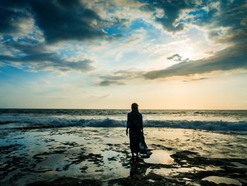 Silhouette woman standing on beach against sky during sunset