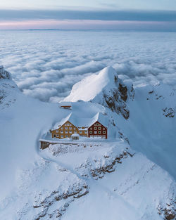 Aerial view of snow covered land and building against sky