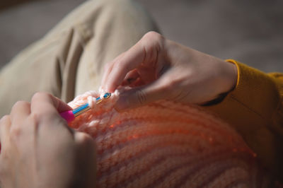 Female hands close-up, crocheting clothes on the sofa at home, handmade