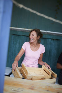 Happy senior gardener with crates sitting on bench at yard