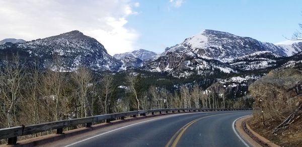 Road amidst snowcapped mountains against sky