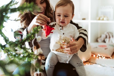 Cute girl holding christmas tree at home