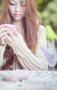 Close-up of beautiful young woman using smart phone at outdoor restaurant