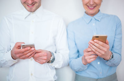 Midsection of man and woman using mobile phones