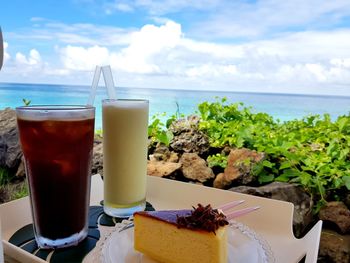 Close-up of drink on table by sea against sky