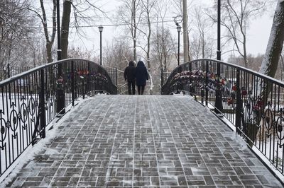 Rear view of man on footbridge in winter