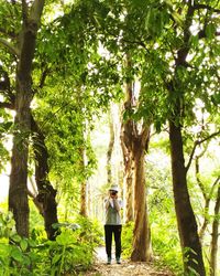 Woman standing by tree in forest