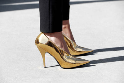 Low section of woman in high heels standing on road