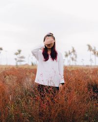 Smiling woman with flowers in hair against sky