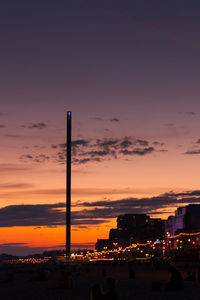 Silhouette built structure at beach against sky at sunset