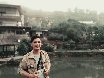 Portrait of smiling woman standing against river