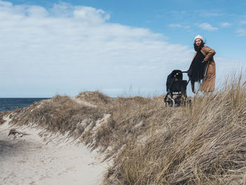 Woman with pram standing on sand dunes