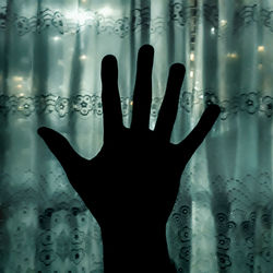 Digital composite image of hand on glass window