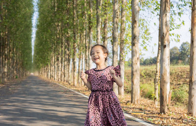 Portrait of young woman standing against trees