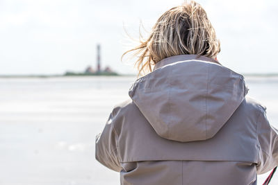 Rear view of woman wearing hooded shirt at beach