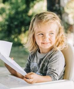 Cute girl with blond hair holding paper