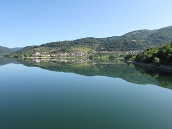 Scenic view of lake and mountains against clear blue sky