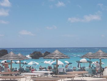 People enjoying at beach during summer against sky