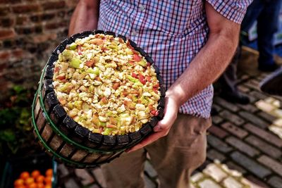 Midsection of man holding crushed apple in container