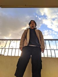 Low angle portrait of man standing against sky