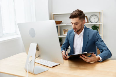 Young man using laptop at desk in office