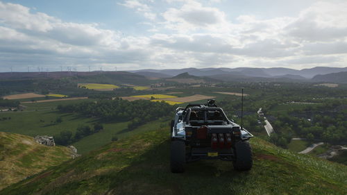 Car on road amidst field against sky