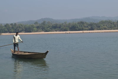 Man standing on boat in lake against sky