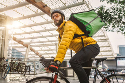 Man standing with bicycle on street in city