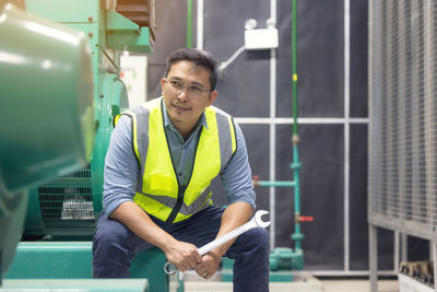 Portrait of worker or technician man hold wrench, smile and stand at generator room