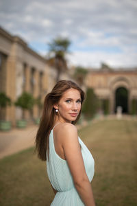 Portrait of young woman standing against building