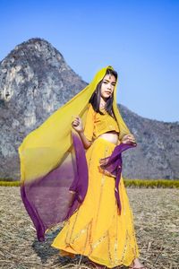 Woman standing on yellow umbrella against mountain