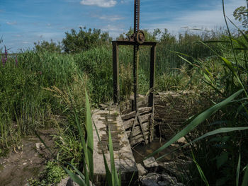 Wooden post on grass against sky