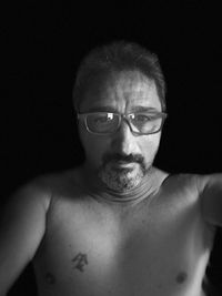 Portrait of shirtless man against black background