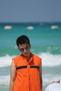 Portrait of man wearing sunglasses while standing at beach
