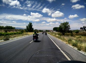 Rear view of man riding motorcycle on road against sky