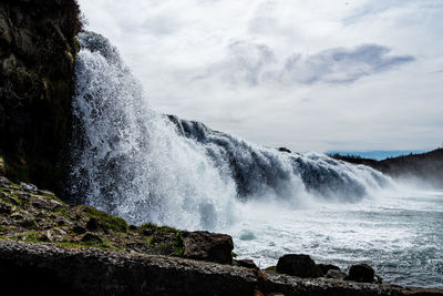 Scenic view of waterfall against sky